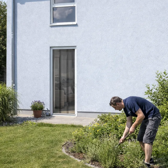 Mann bei der Gartenarbeit vor Terrassentür mit Fliegengitter-Lamellen flexibler Insektenschutz für Balkon und Terrasse